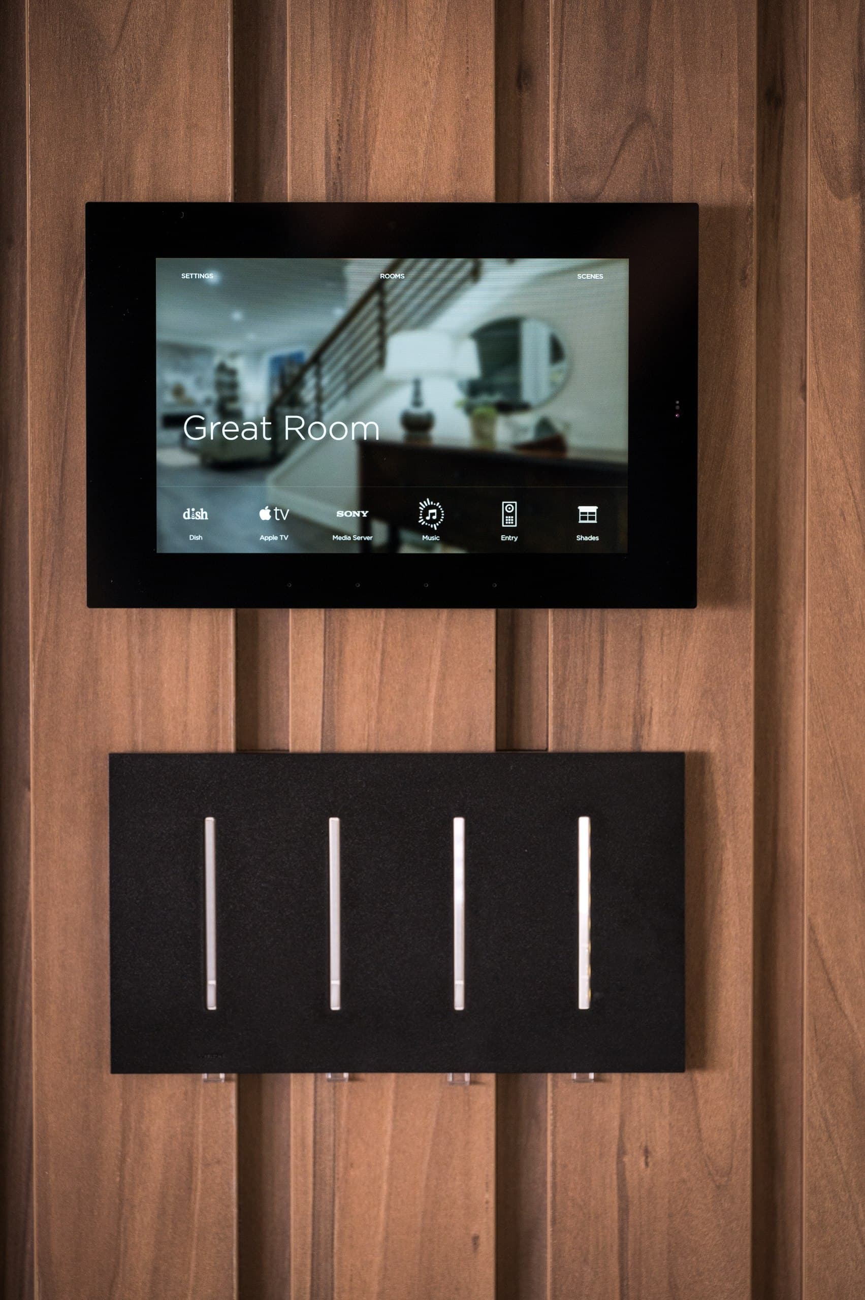 Smart home touch panel and Lutron Grafik T keypads on walnut wall
